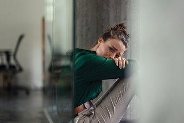 Eine junge Frau sitzt verzweifelt im Büro.