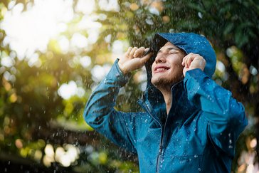 Ein Mann genießt fröhlich den Regen.